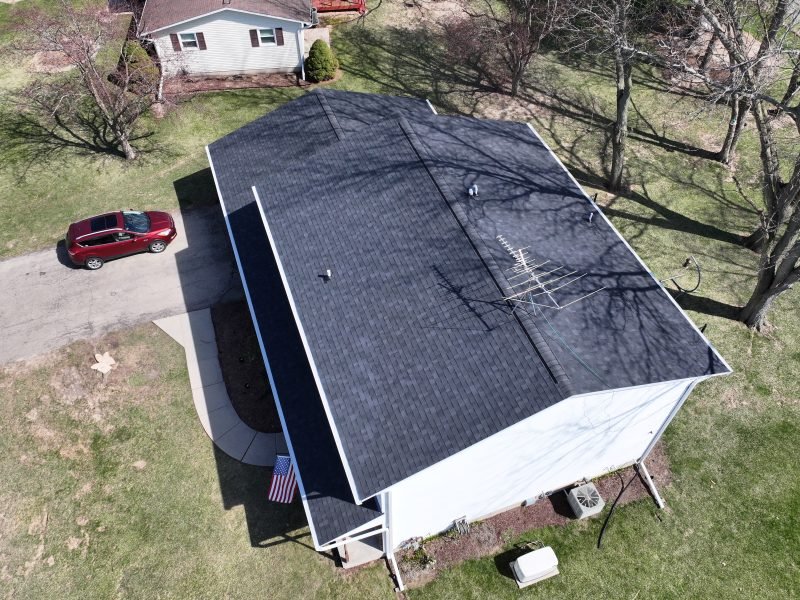 A detached garage with a new charcoal shingle roof matching the house