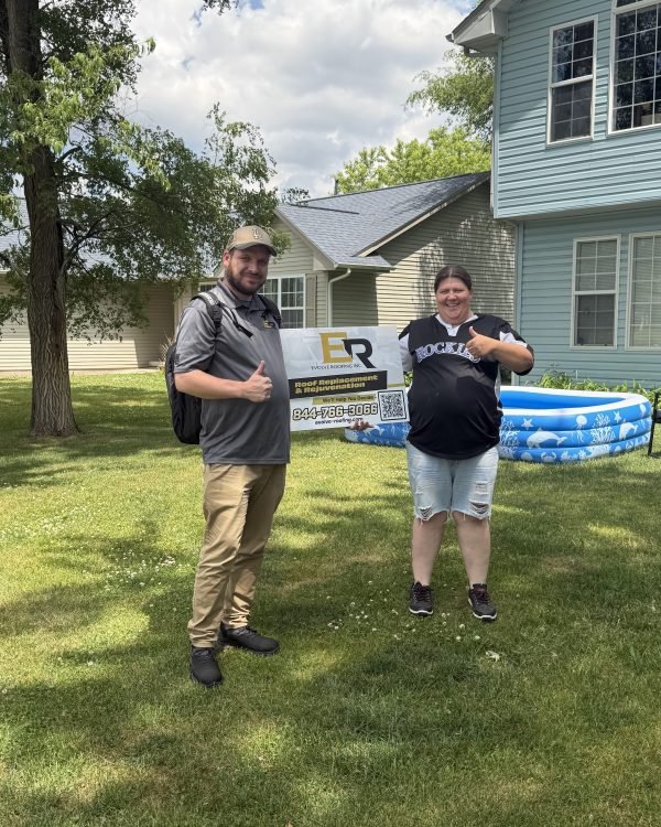 One of our crew and a homeowner holding the Evolve Roofing yard sign in the front yard