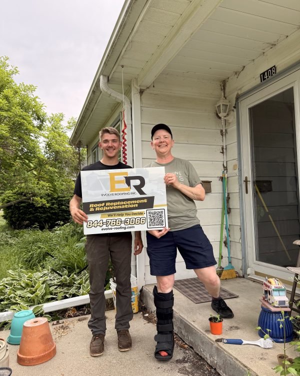 Two men on a front porch holding the Evolve Roofing sign with the phone number
