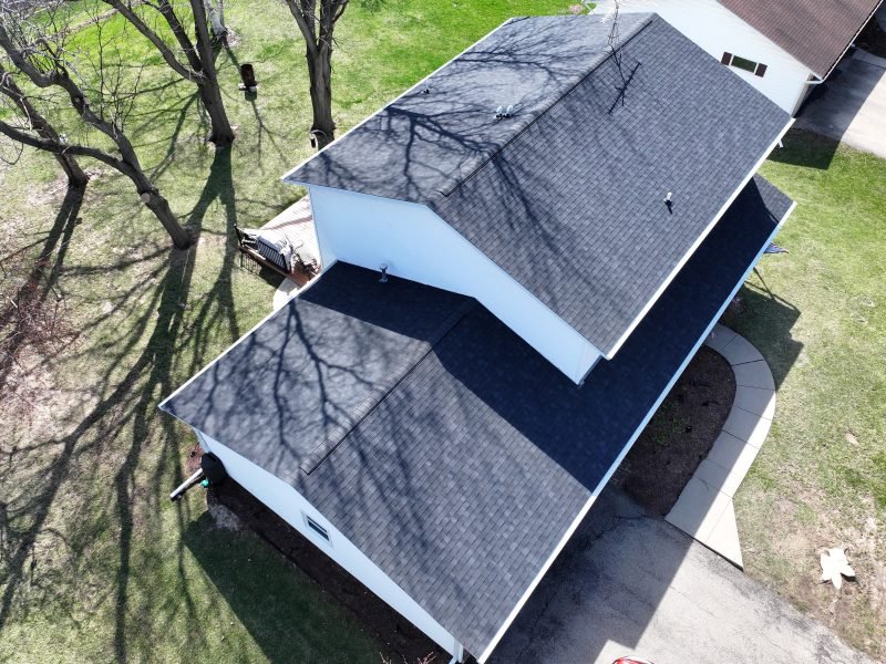 A new charcoal architectural shingle roof on a white ranch home, photographed from above after the job